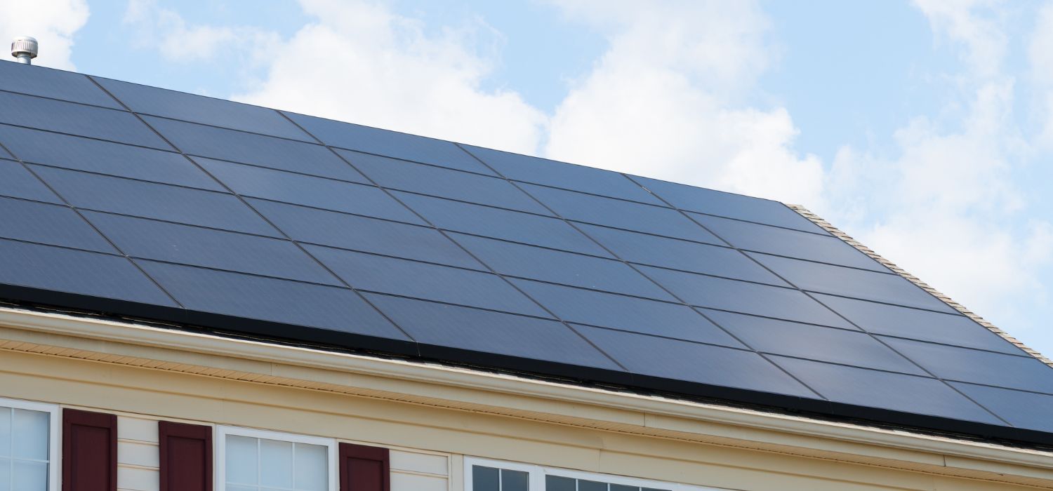 Rooftop solar panels installed on a residential home under a partly cloudy sky, illustrating a typical residential solar energy system.