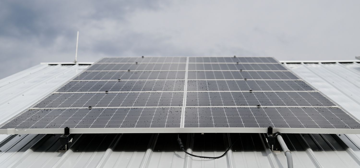 Close-up view of solar panels seamlessly integrated on a metal roof under a cloudy sky.